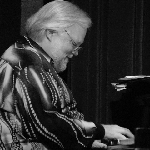 Larry Dunlap smiles while playing piano